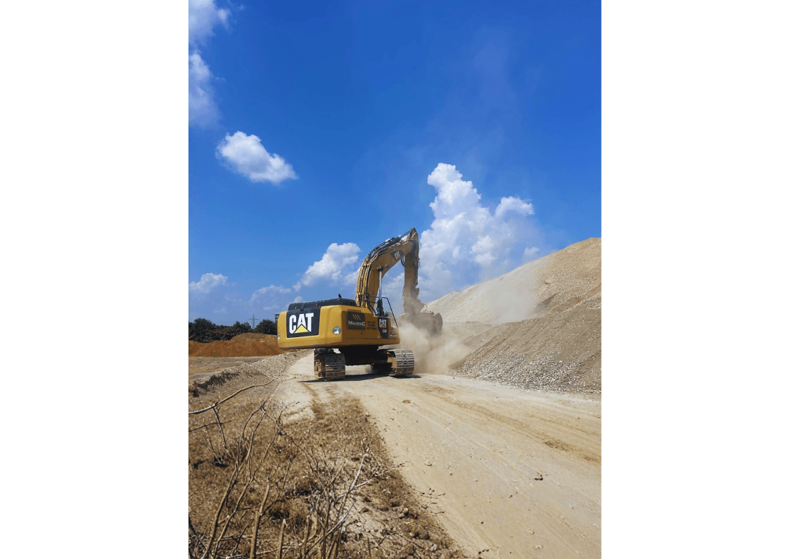 Maveric excavator and crew placing a precast concrete unit in falling snow — contractor delivery in progress on a live civils site.
