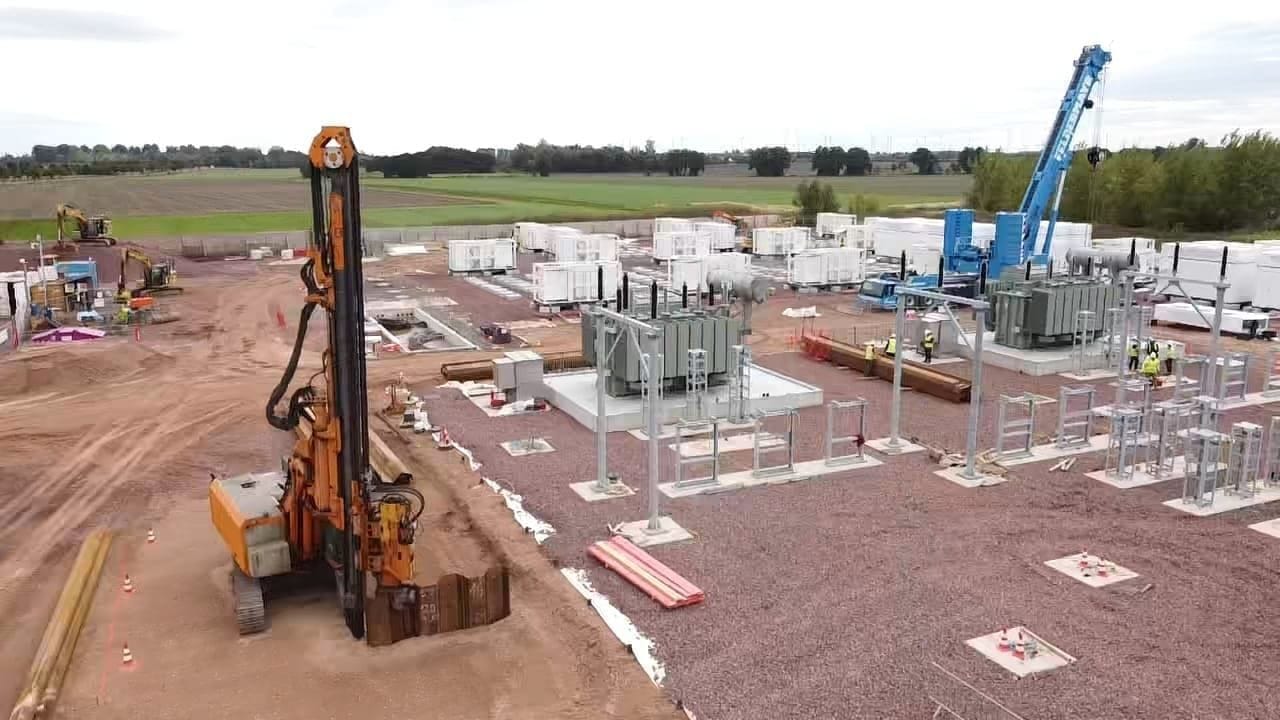 Aerial view of a live Maveric civils site — a piling rig, transformer bases and a mobile crane across a substation and battery-storage compound.